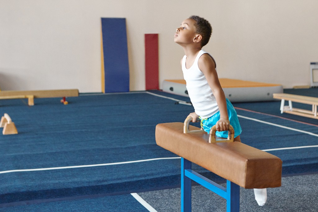 Young recreational gymnast training on pommel horse